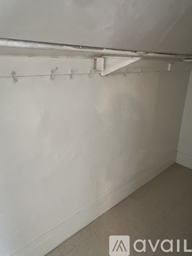 A white wall with a row of hooks on it.