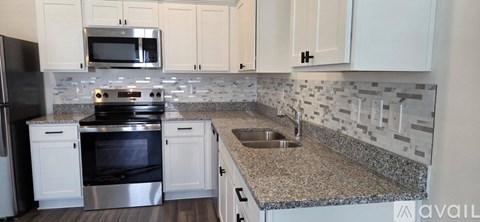 A kitchen with a granite counter top and a stove top oven.