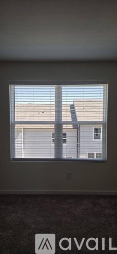 A window with blinds overlooking a building.