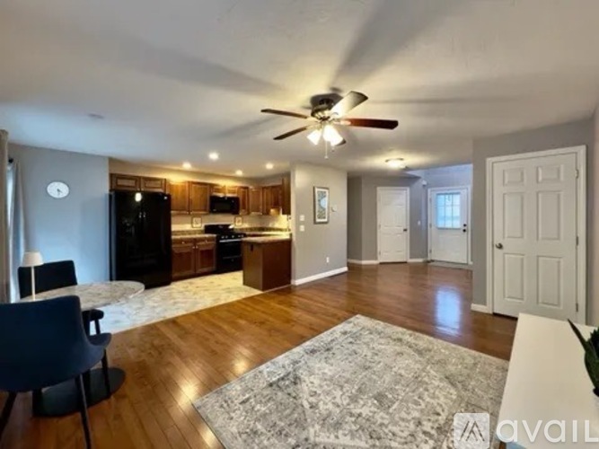 A living room with a ceiling fan and a dining table with chairs.