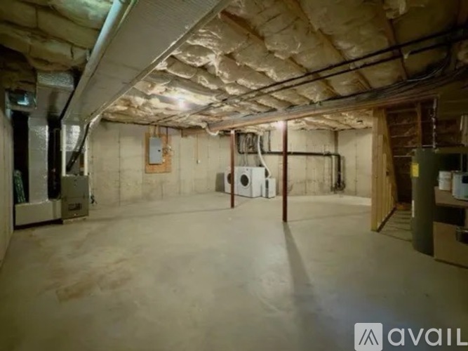 A spacious basement with a concrete floor and walls, equipped with a washer and dryer, and a furnace.