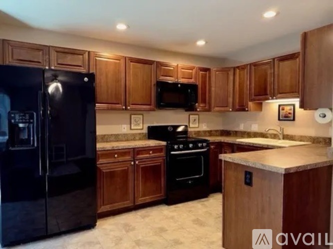 A kitchen with wooden cabinets and black appliances.