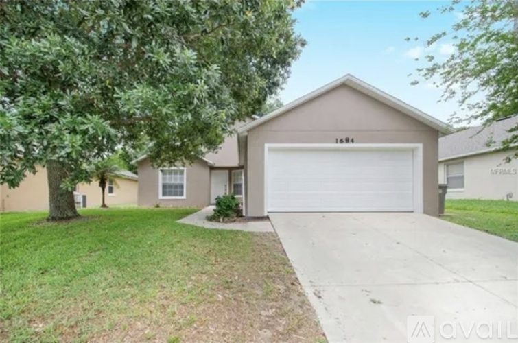 A house with a garage and a tree in front.