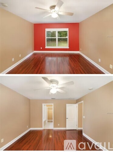A room with a red wall and wooden floors.