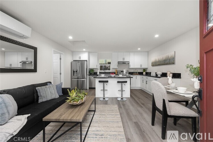 A modern kitchen with a black sofa and a wooden table.