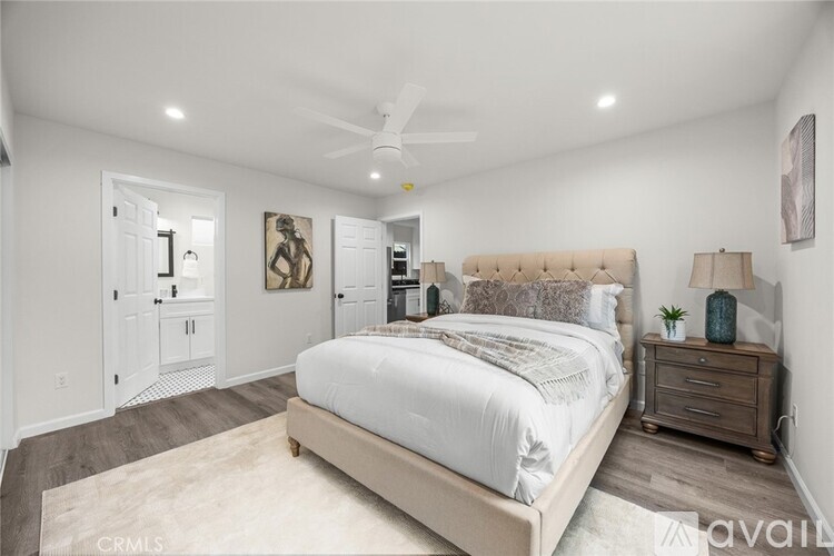 A bedroom with a large bed, a ceiling fan, and a rug on the floor.