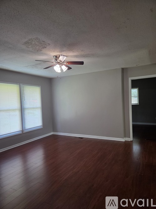 A room with a ceiling fan and wooden flooring.