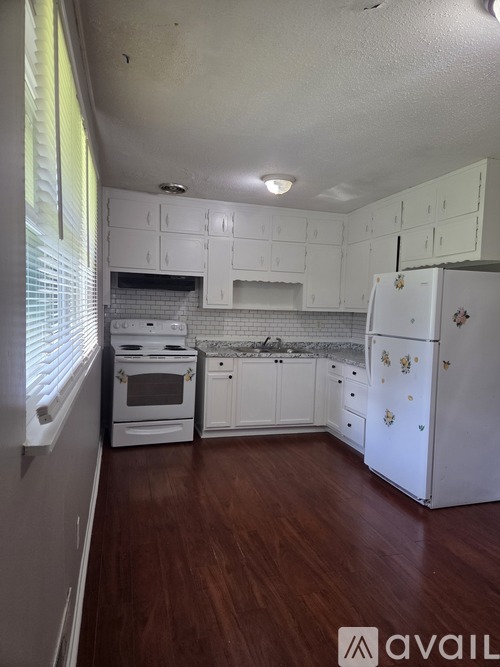 A kitchen with white cabinets and a white fridge.