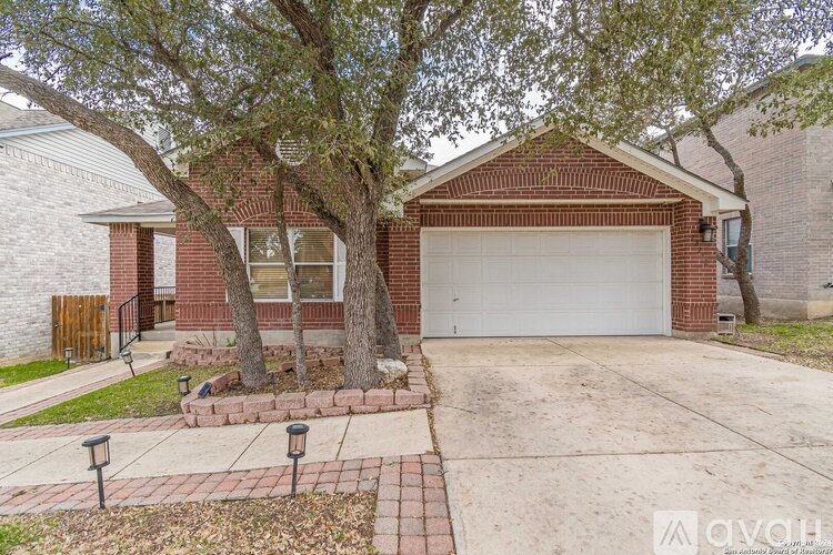 A red brick house with a white garage door and a tree in front.