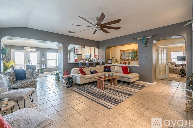A spacious living room with a white sofa set and a wooden coffee table.