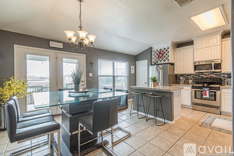 A kitchen with a glass table and black chairs.