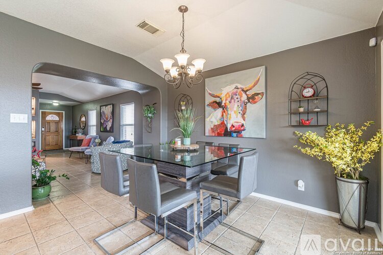 A dining room with a glass table and grey chairs.