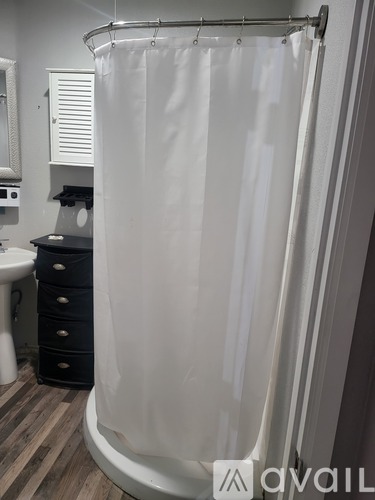 A white shower curtain is hanging in a bathroom.