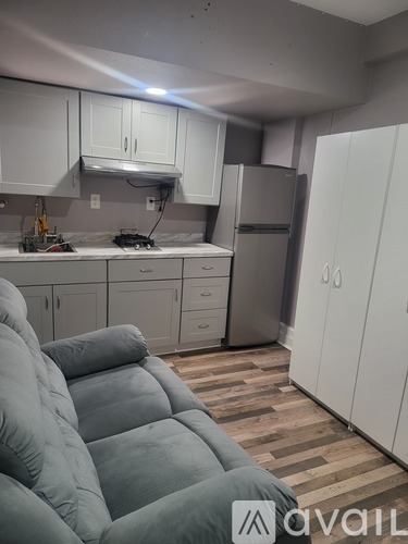A kitchen with white cabinets and a grey couch.