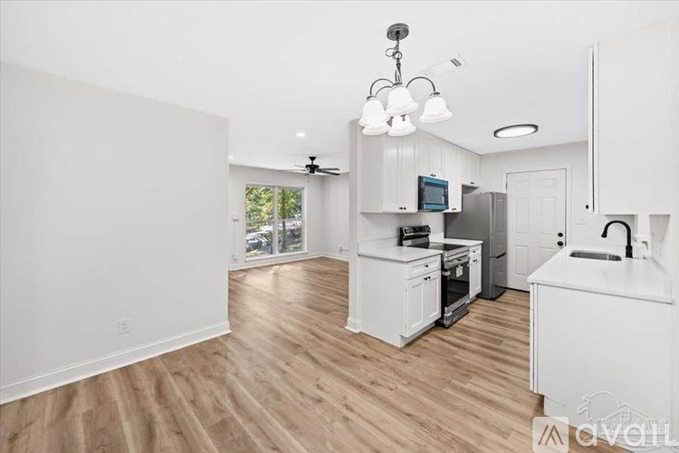 A kitchen with white cabinets and a wooden floor.