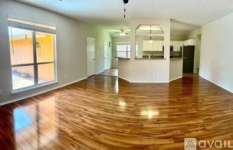A spacious room with wooden flooring and a large window.
