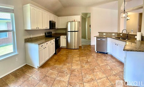 A kitchen with white cabinets and a tiled floor.