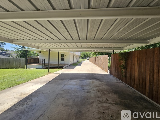 A long concrete pathway leads to a house under a covered walkway.