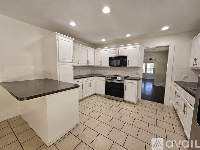 A kitchen with white cabinets and a black countertop.