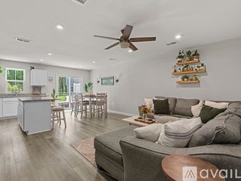 A living room with a grey couch and a ceiling fan.