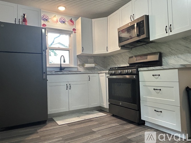 A kitchen with a black refrigerator and white cabinets.