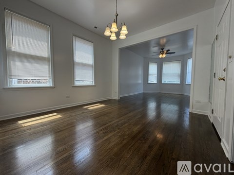 A spacious room with wooden floors and a ceiling fan.