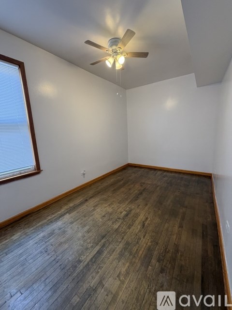 A room with wooden flooring and a ceiling fan.