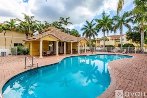 A pool with a small pavilion in front of a row of houses.