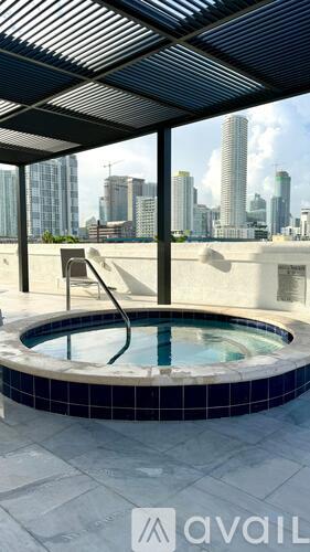 A hot tub on a balcony with a city skyline in the background.