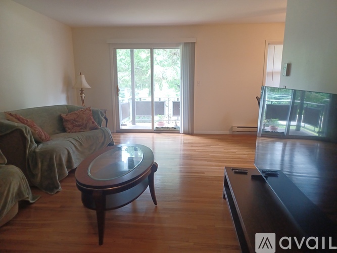 A living room with a couch, a coffee table, and a balcony.