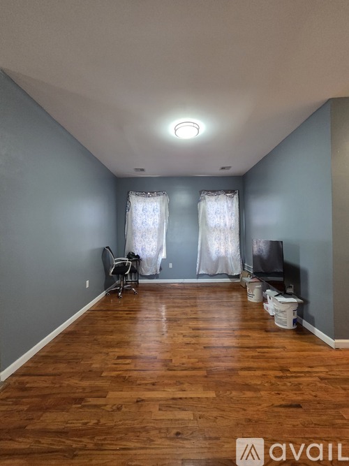 A room with wooden floors and a window with curtains.