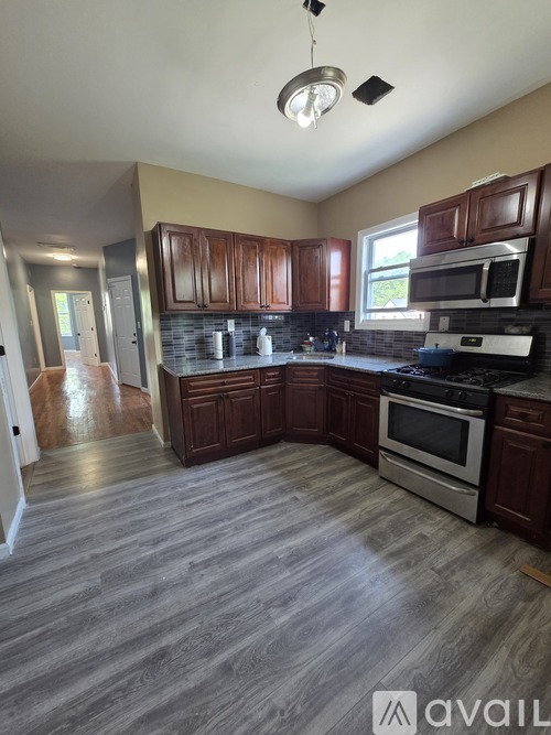 A kitchen with wooden cabinets and a grey floor.