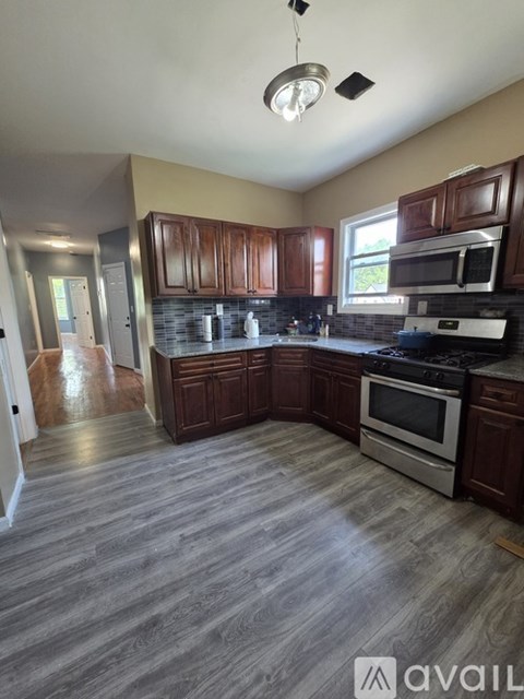 A kitchen with wooden cabinets and a grey floor.