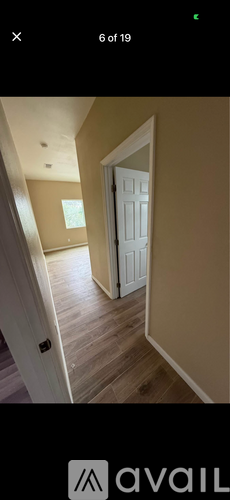 A white door is open in a room with wooden flooring.