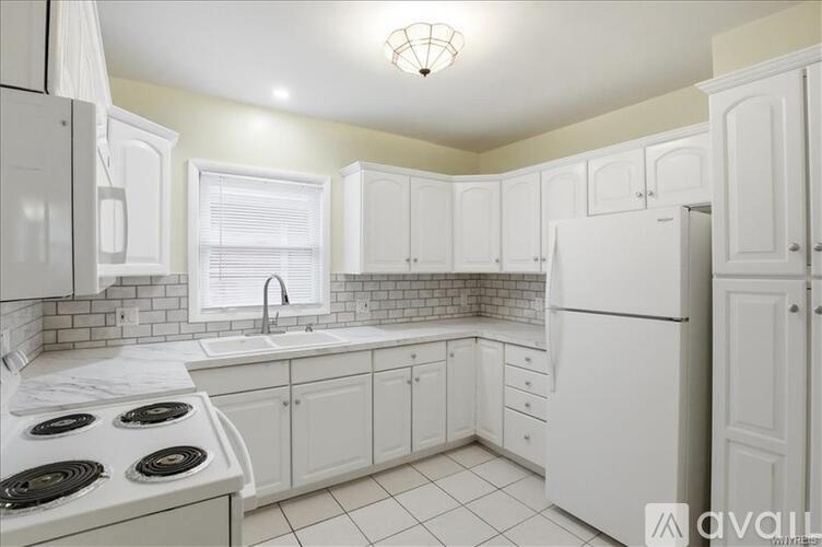 A kitchen with white cabinets and a white refrigerator.