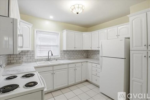 A kitchen with white cabinets and a white refrigerator.