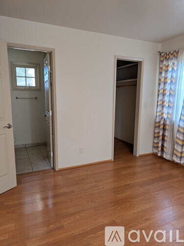 A room with wooden floors and two doors, one of which is open.