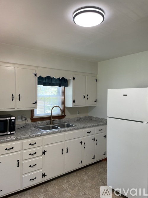A kitchen with white cabinets and a white refrigerator.