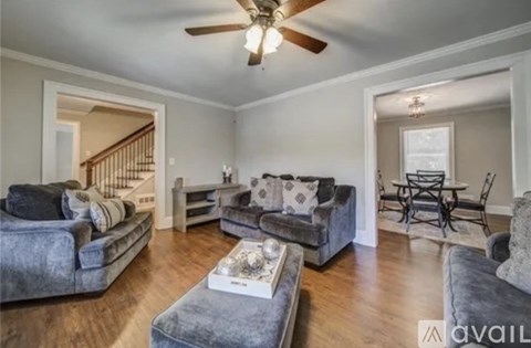 A living room with grey couches and a ceiling fan.