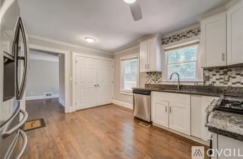 A kitchen with white cabinets and a black and white tiled backsplash.