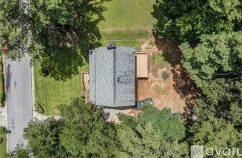 A house with a grey roof is surrounded by greenery.