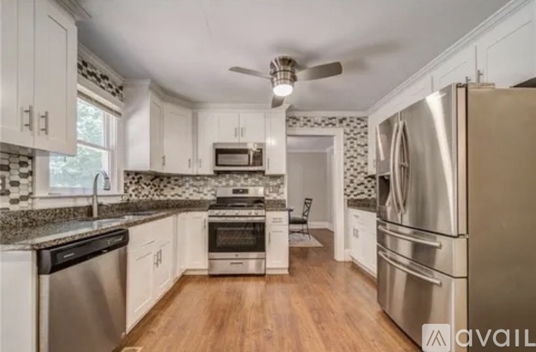 A kitchen with white cabinets and a stainless steel refrigerator.