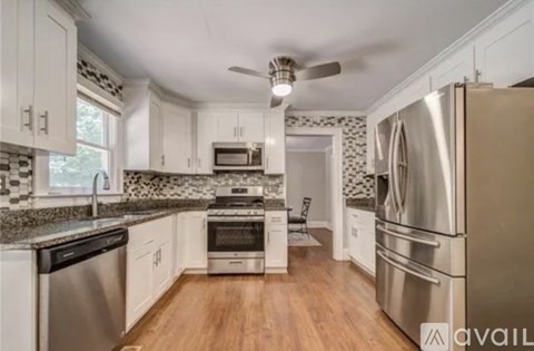 A kitchen with white cabinets and a stainless steel refrigerator.