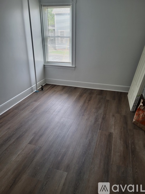 A room with wooden flooring and a window with blinds.