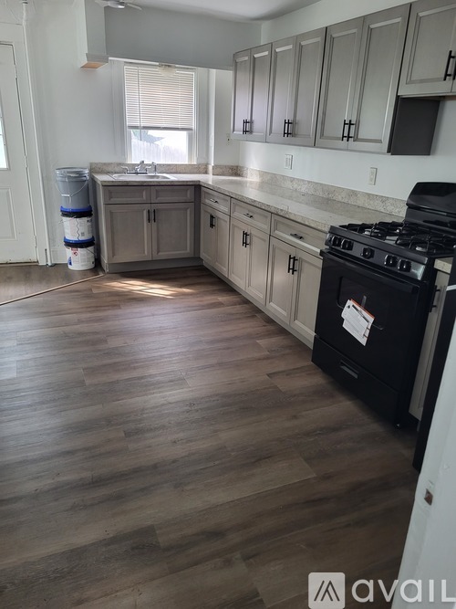 A kitchen with a black stove top oven and wooden floors.