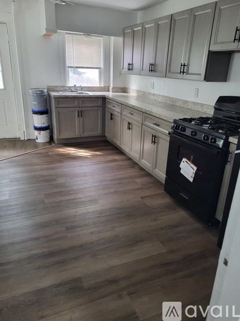 A kitchen with a black stove top oven and wooden floors.