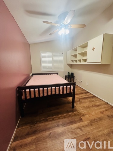 A bedroom with a bed, a ceiling fan, and a cabinet.