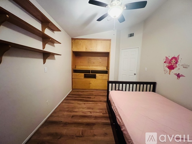 A room with a bed, a ceiling fan, and a wall with a butterfly decal.