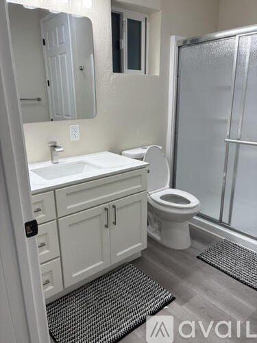 A bathroom with a toilet, sink, and mirror.