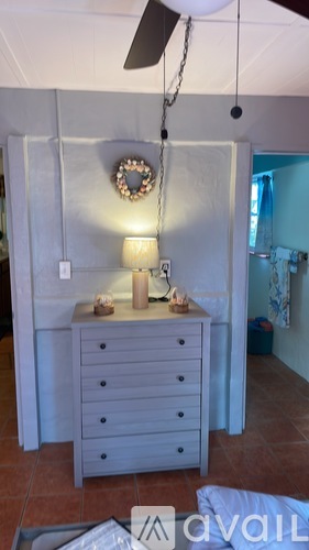 A bedroom with a dresser and a ceiling fan.